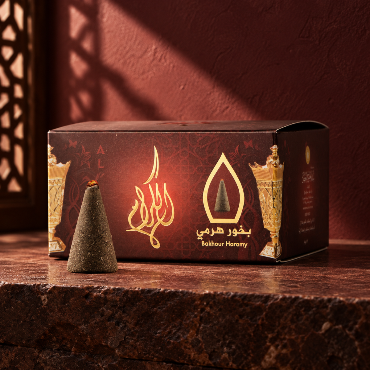 Al-Keram Pyramid Bakhoor 50 g from Sedr Al-Khaleej; maroon incense box with one cone on reddish-brown stone against a maroon wall in angled sunlight.