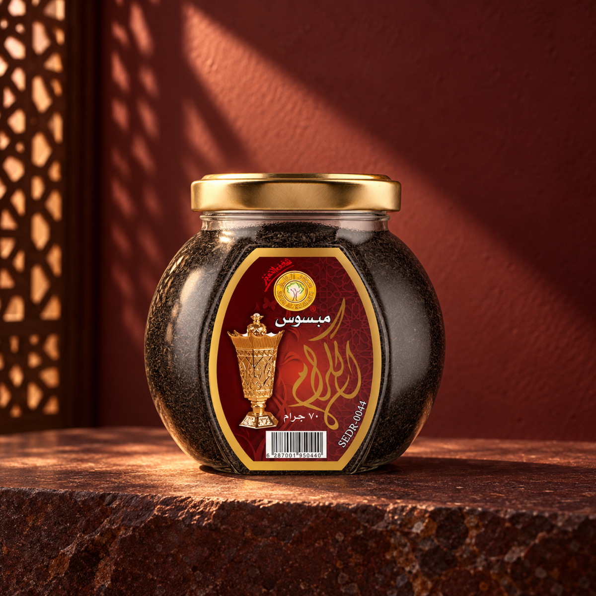 Al-Keram Mabsos 70 g from Sedr Al-Khaleej; round glass jar with a maroon label and gold lid on reddish-brown stone against a maroon wall.