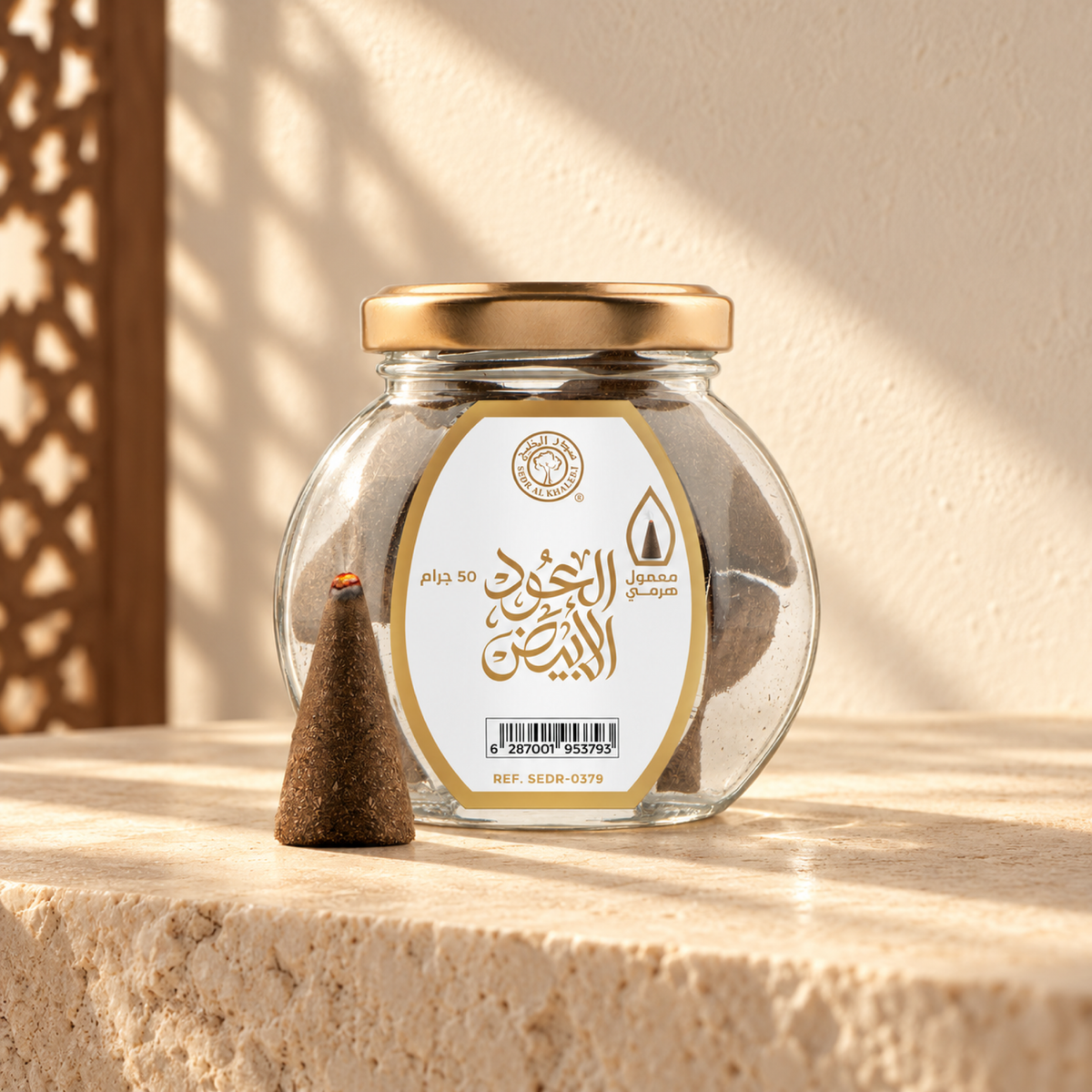 Al Oud Al Abyad Pyramid Maamoul 50 g from Sedr Al-Khaleej; round glass incense jar with a white label, gold lid and one cone on cream stone in angled sunlight.