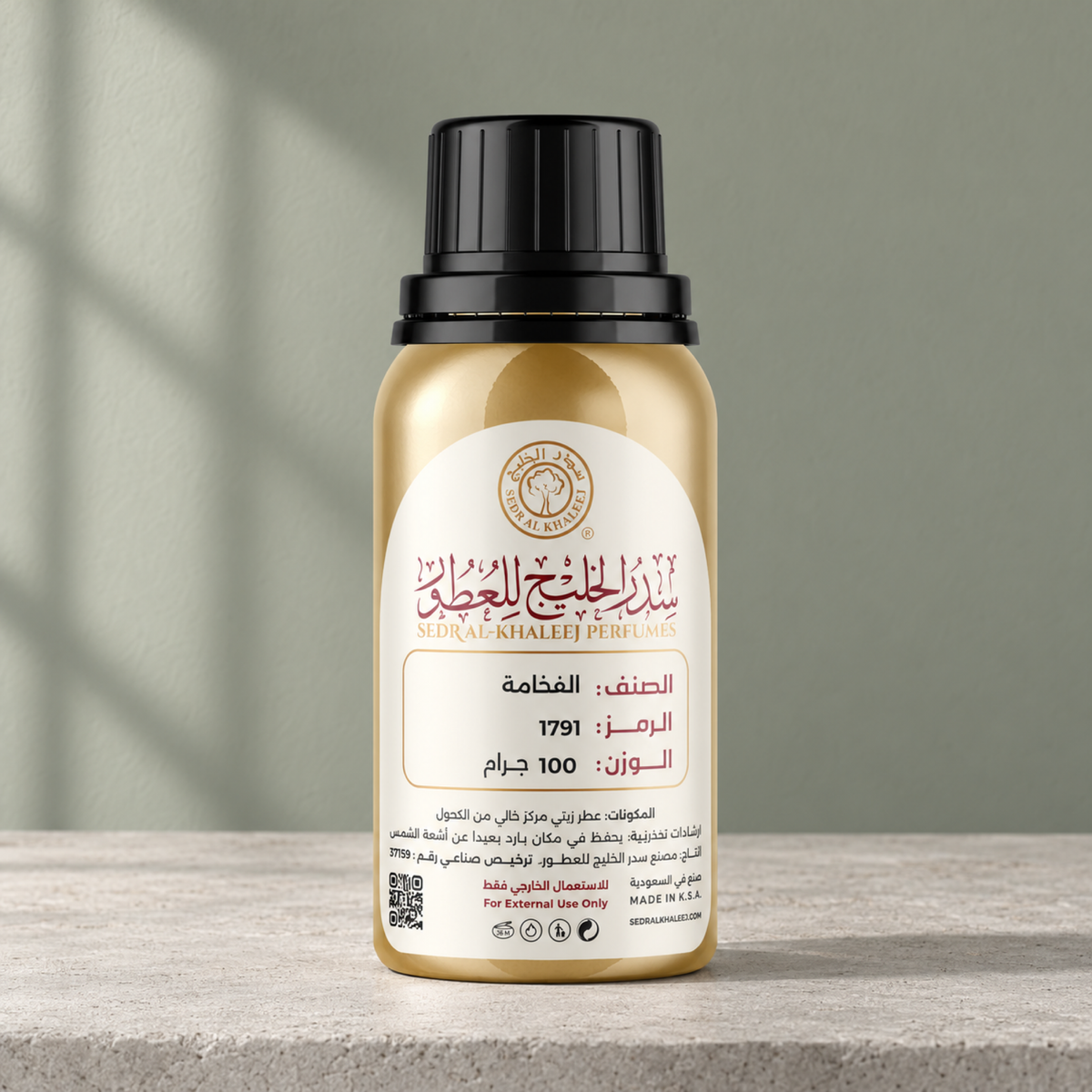 Sedr Al-Khaleej Al Fakhama perfume oil, gold bottle on pale cement against a sage wall with a morning window shadow