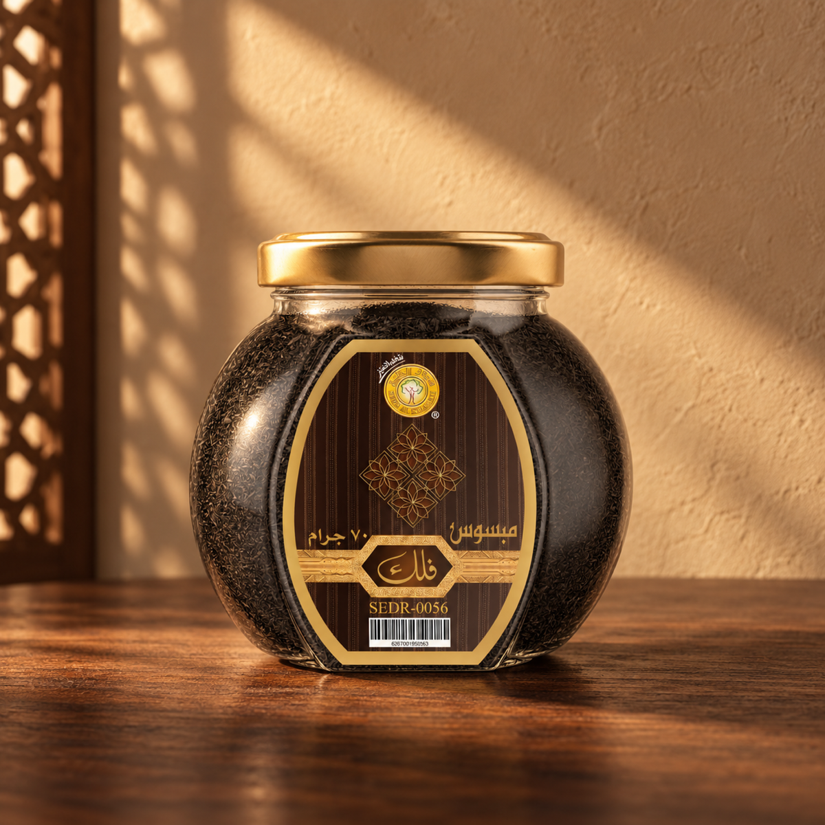 Falak Mabsos 70 g from Sedr Al-Khaleej; closed glass jar with a gold lid and brown label on walnut wood against a sand plaster wall, with angled sunlight and a wooden screen shadow.
