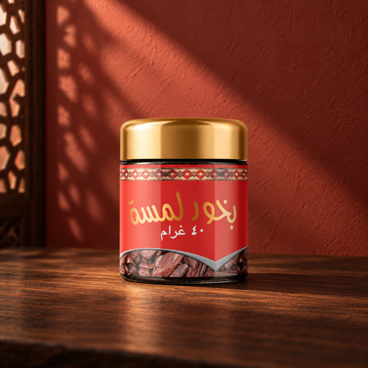 Lamsa Bakhoor 40 g from Sedr Al-Khaleej; incense jar with a gold lid and red label on wood against a red sunlit wall.