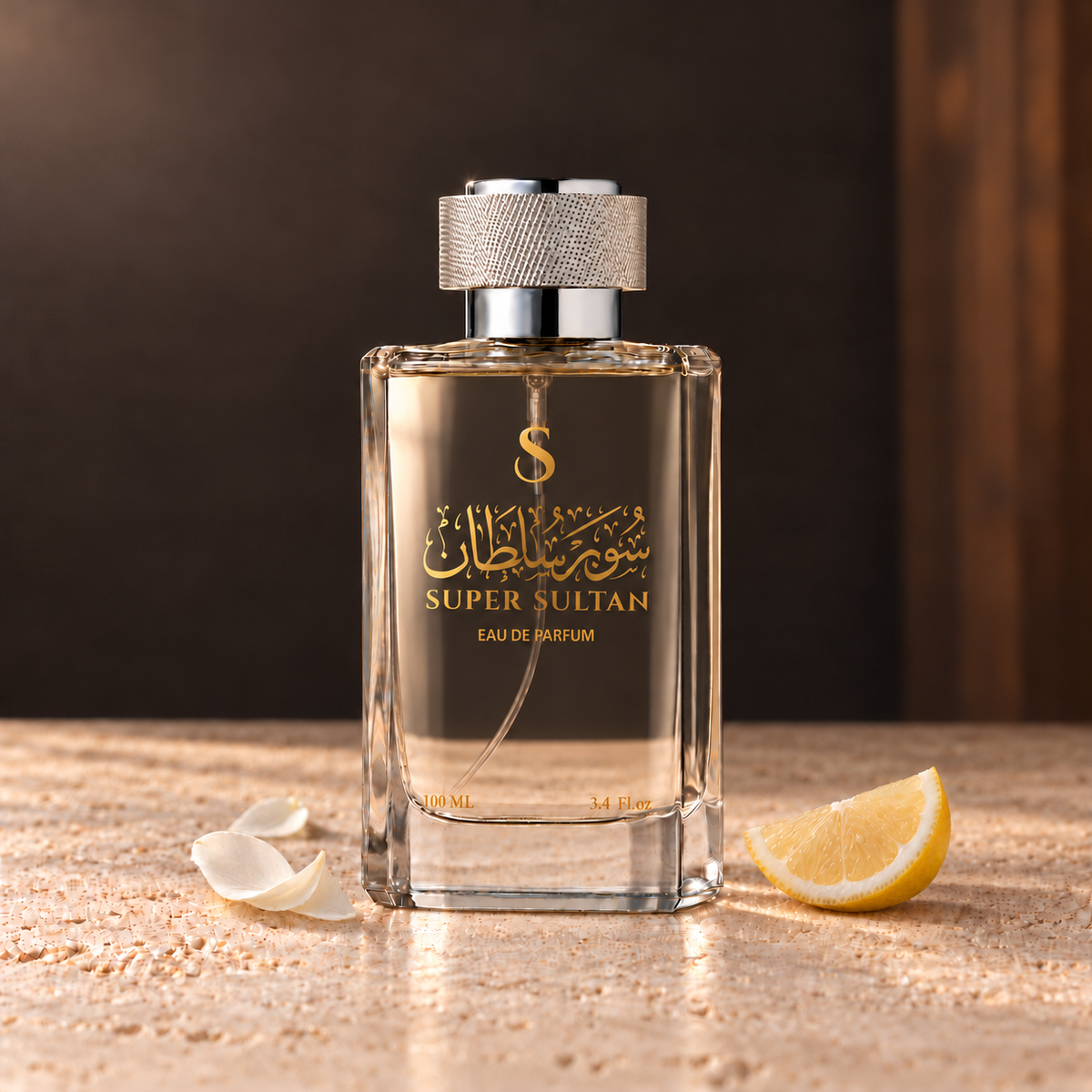 زجاجة عطر سوبر سلطان 100 مل بغطاء فضي وبصمة ذهبية مع قطعة حمضيات وبتلات فاتحة على سطح حجري وإضاءة دافئة